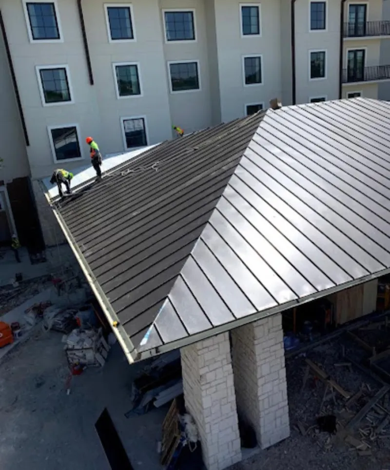 Crew installing standing seam metal roof panels on a commercial project in Peters